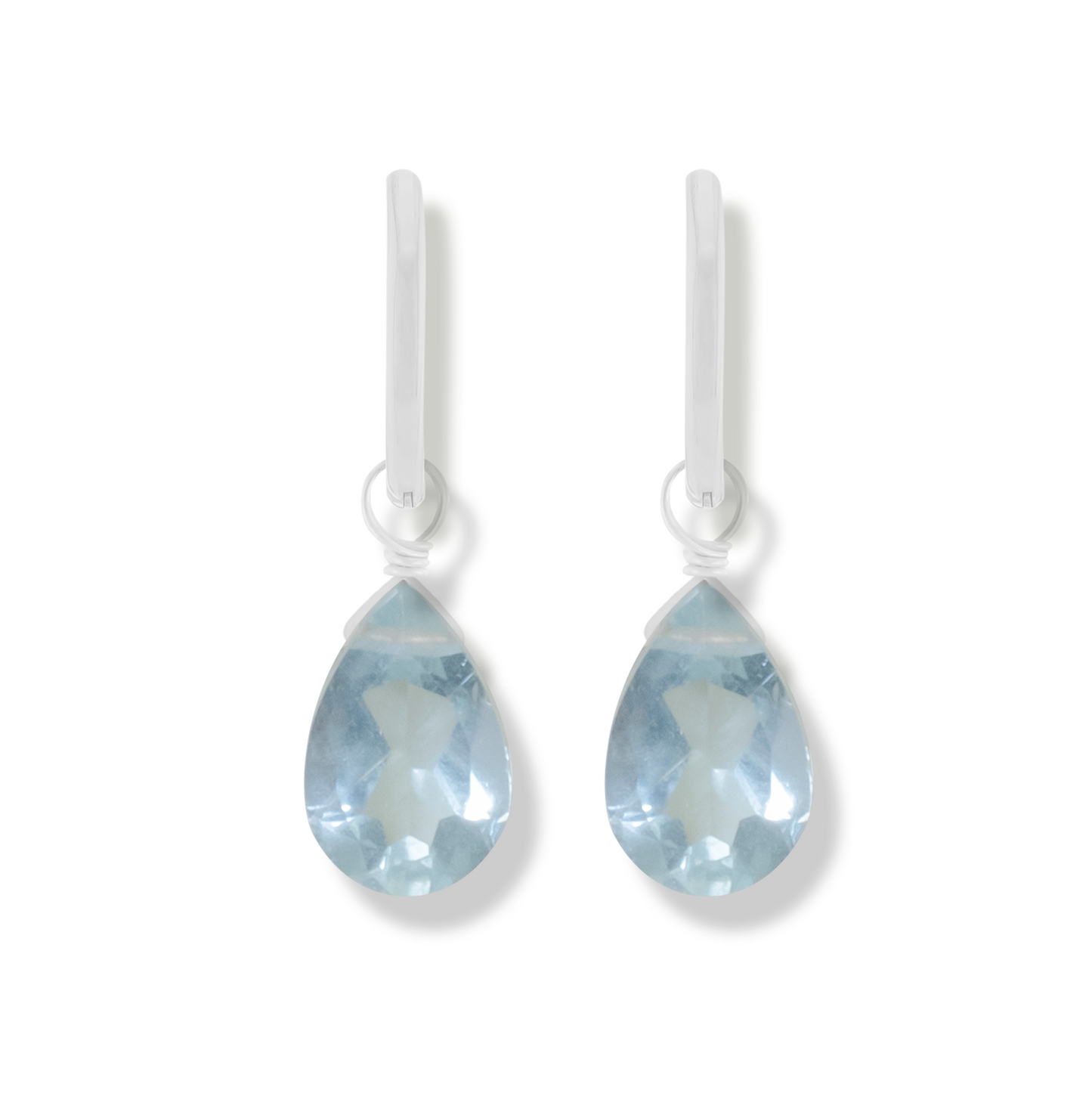 pair of silver earrings with aquamarine pear cut gemstones on a white background.