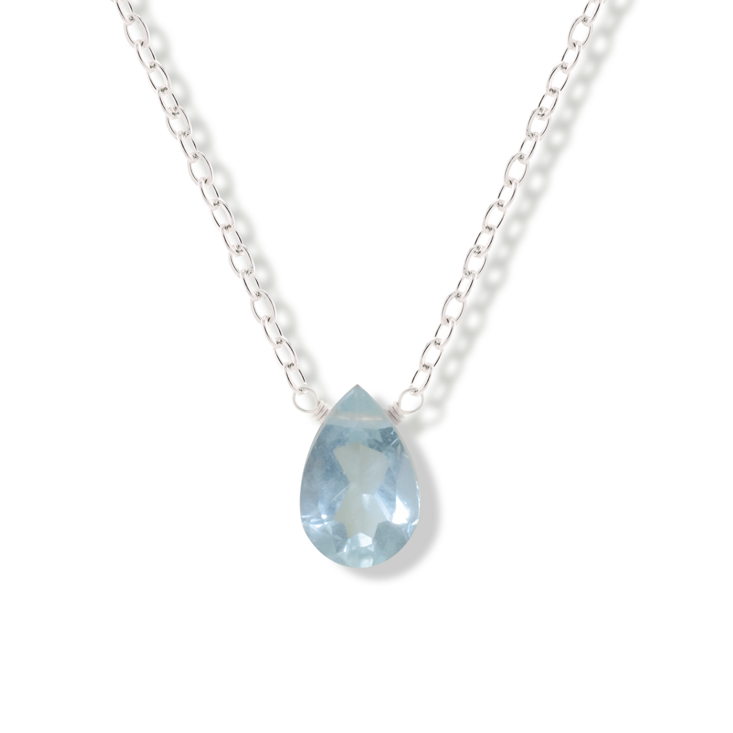 Aquamarine pear cut gemstone pendant on a sterling silver chain on a white background.
