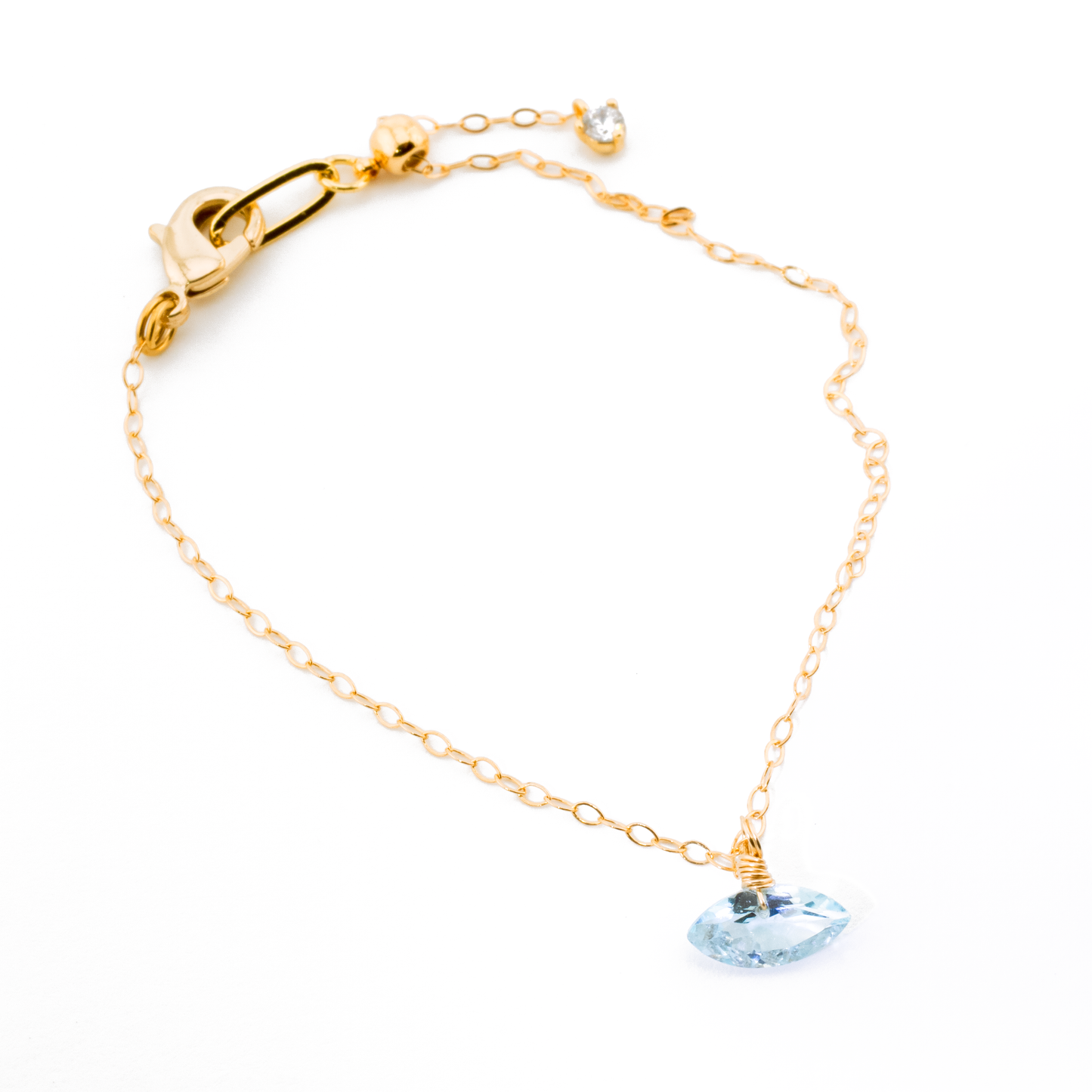 Gold bracelet with a blue topaz marquise cut gemstone on a white background