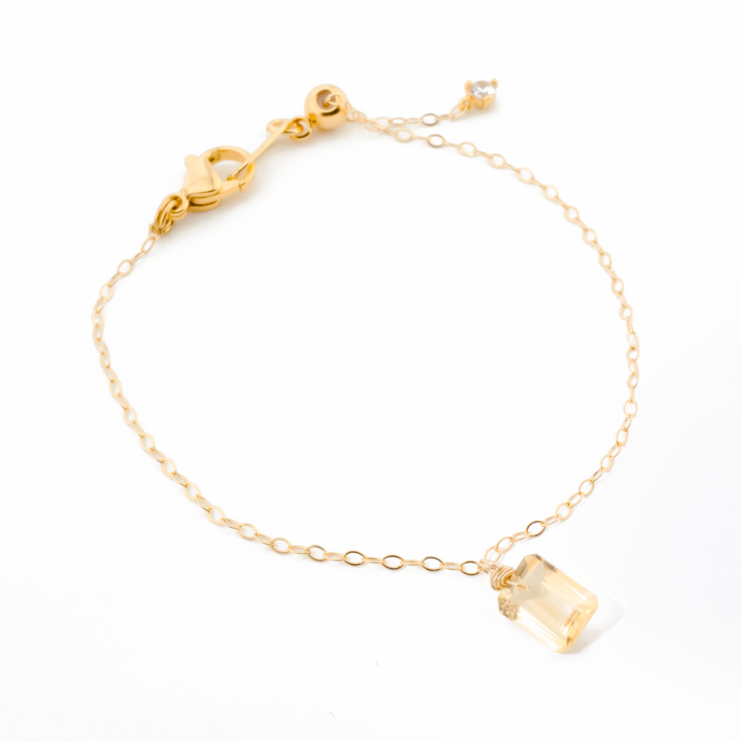 Gold bracelet with a citrine gemstone on a white background