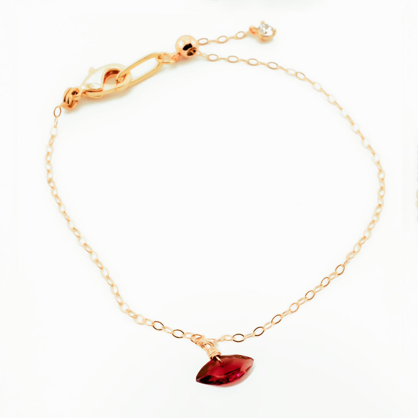 Gold bracelet with a garnet marquise cut gemstone on a white background