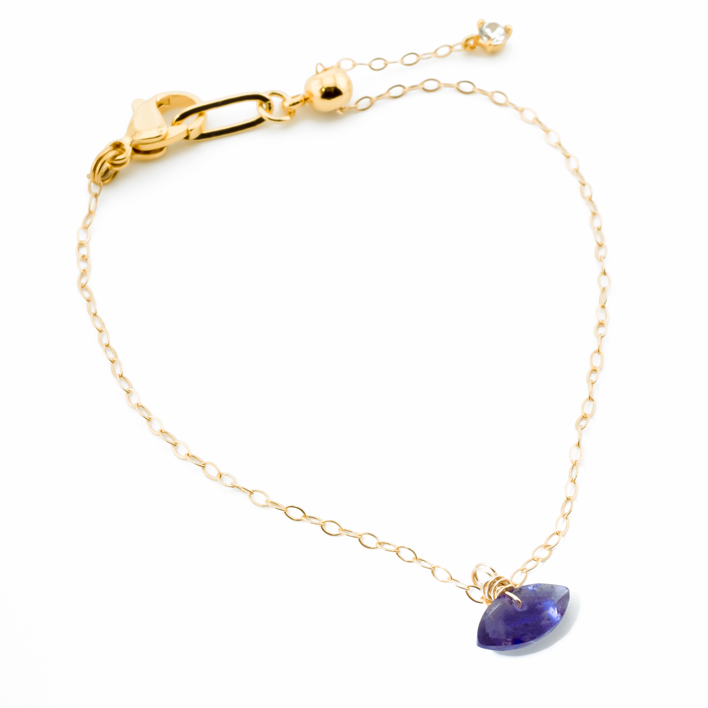 Gold bracelet with a iolite marquise cut gemstone on a white background