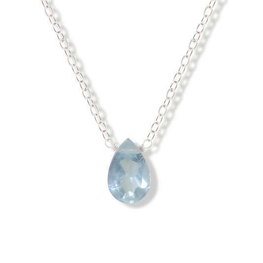 Aquamarine pear cut gemstone pendant on a sterling silver chain on a white background.