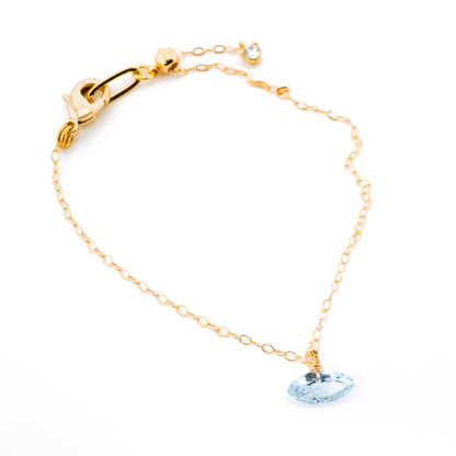 Gold bracelet with a blue topaz marquise cut gemstone on a white background