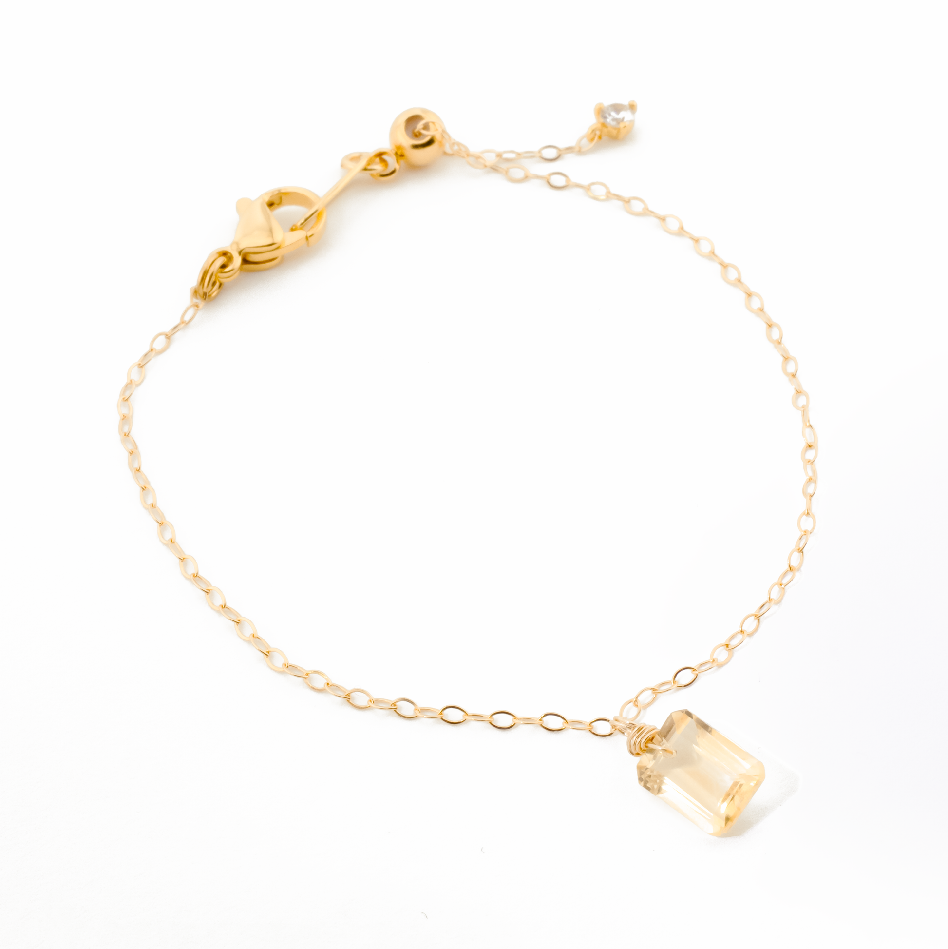 Gold bracelet with a citrine gemstone on a white background