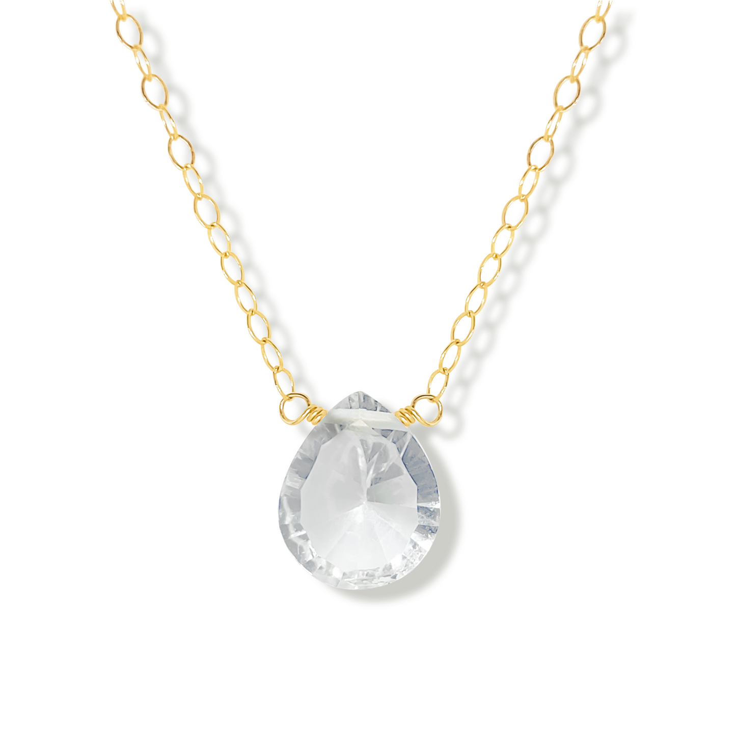 Gold necklace with a rock crystal pear cut shaped pendant on a white background