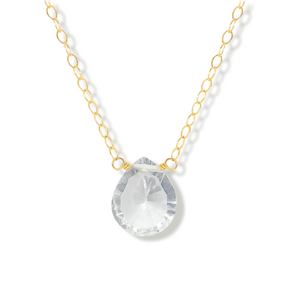 Gold necklace with a rock crystal pear cut shaped pendant on a white background