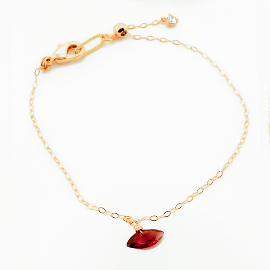 Gold bracelet with a garnet marquise cut gemstone on a white background