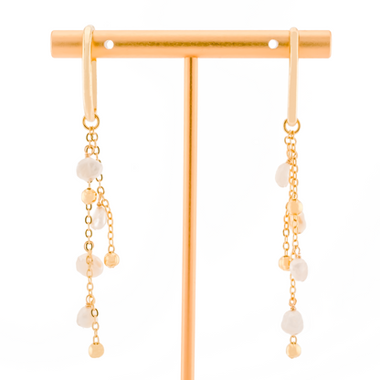pair of gold ear cuffs with detachable charm of baroque pearls on gold chain on a white background.
