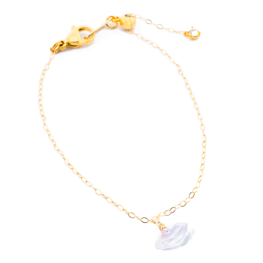 Gold bracelet with a rose quartz marquise cut gemstone charm on a white background