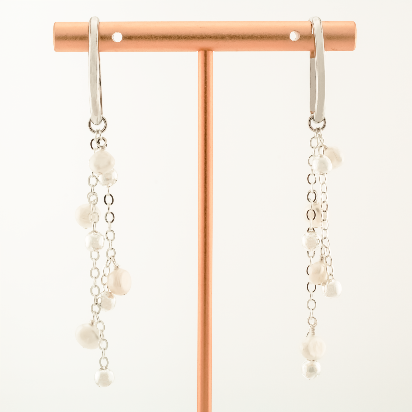 pair of pearl dangle earrings on ear cuffs on a white background