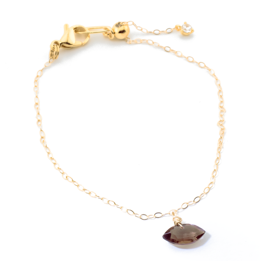 Gold bracelet with a smoky quartz marquise cut charm on a white background